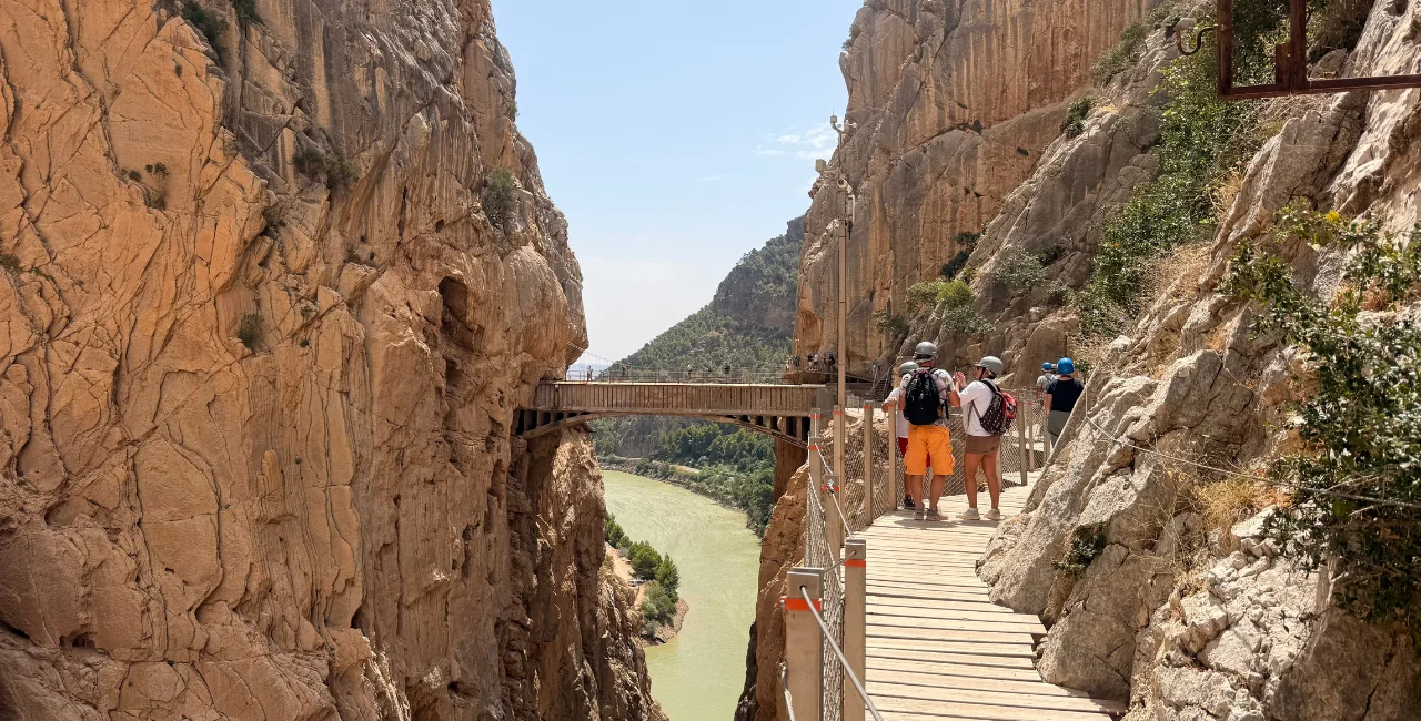 Visitantes con casco recorriendo las pasarelas de madera junto a la pared del desfiladero de los Gaitanes